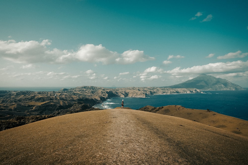 person standing on brown rock formation under blue sky during daytime