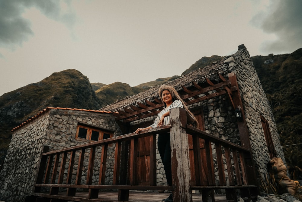 woman in white and black stripe long sleeve shirt standing on brown wooden stairs