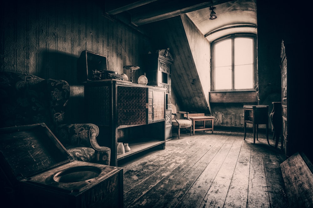 grayscale photo of wooden chair near window