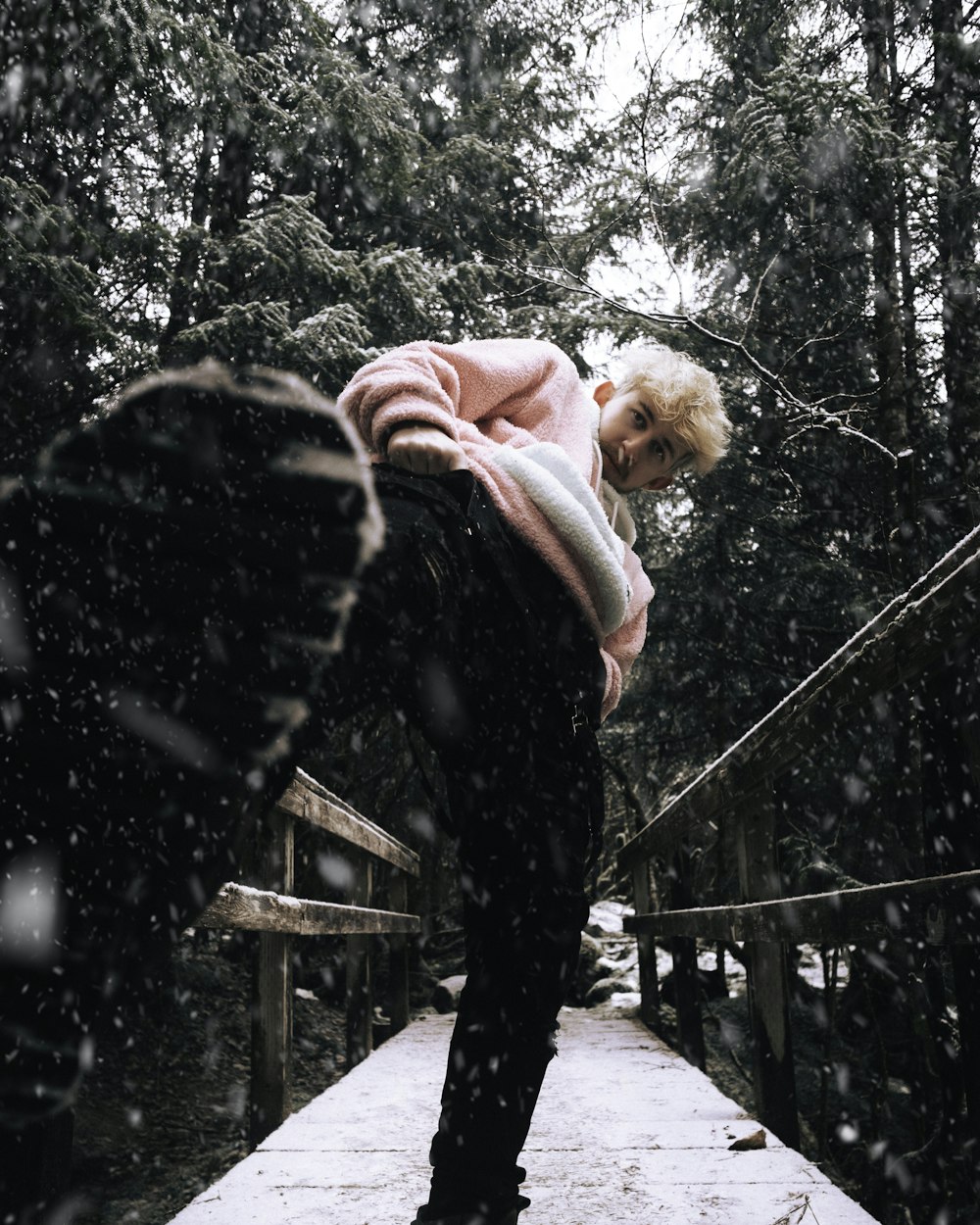 woman in pink and white striped long sleeve shirt and black pants climbing on black metal