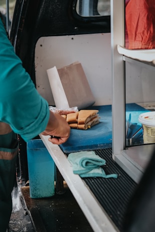 Staff member happily preparing sandwiches while checking orders on a tablet.