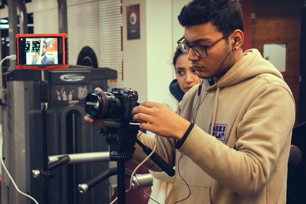 man in brown jacket holding black dslr camera