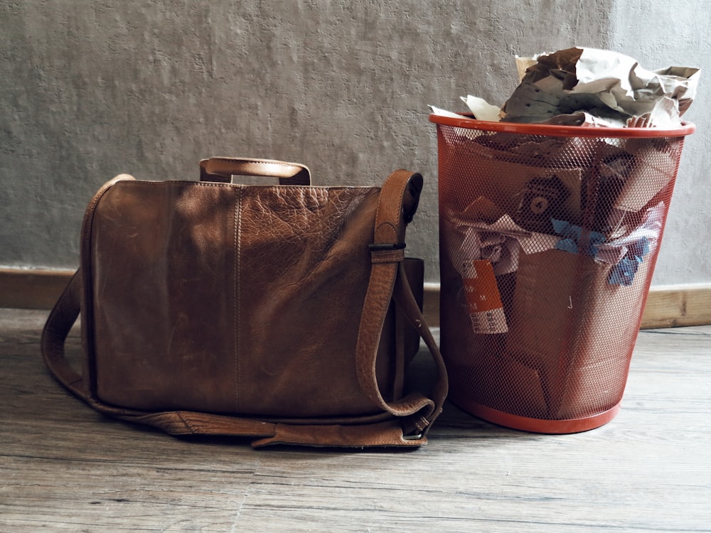 brown leather sling bag on gray wooden table