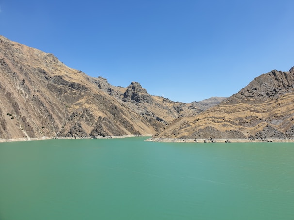 A serene turquoise lake framed by towering Rocky Mountain peaks under a clear blue sky.
