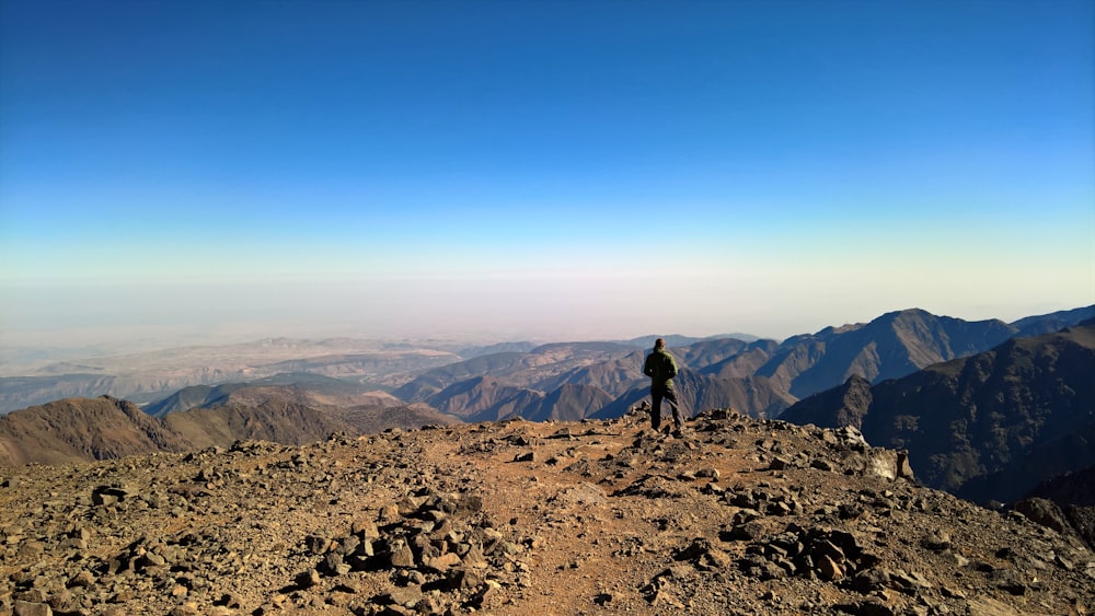 man in black jacket standing on rocky mountain during daytime