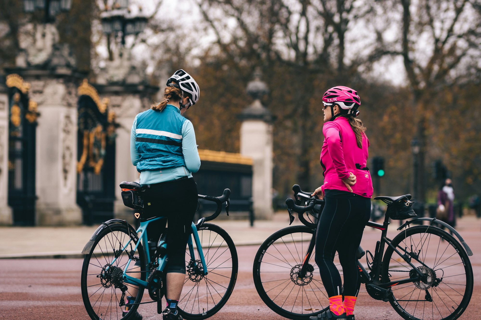 Two women on bikes riding around London with a stop at Buckingham Palace