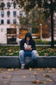 woman in blue denim jeans reading book sitting on blue concrete bench during daytime