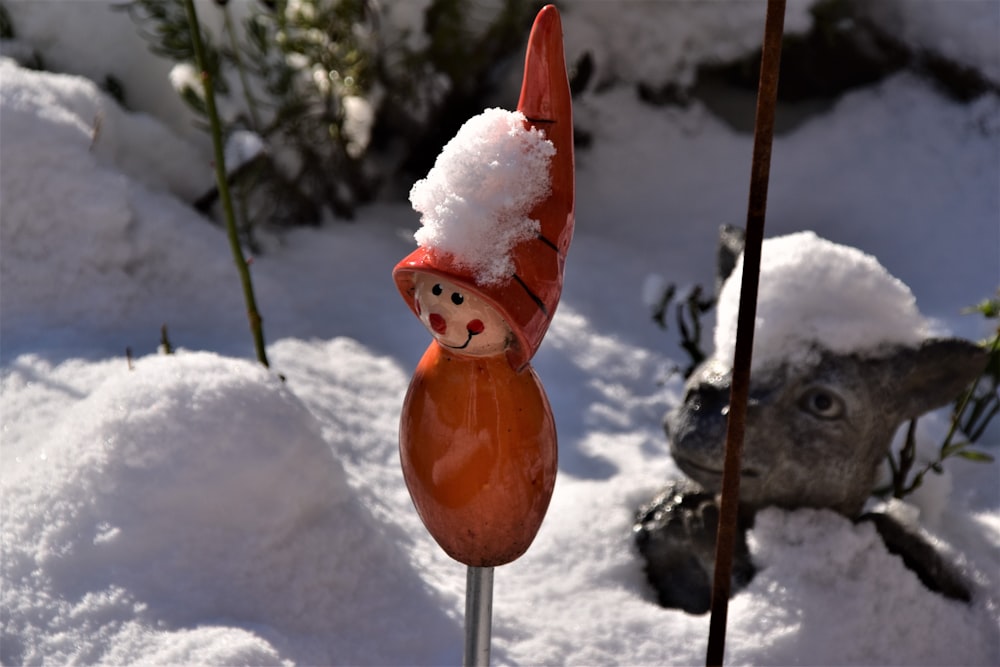 figurita de pájaro naranja en suelo cubierto de nieve