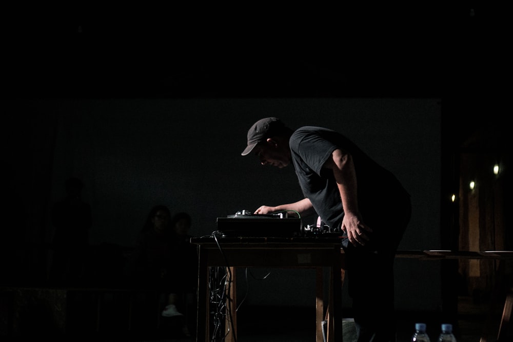 man in black t-shirt and black pants playing piano