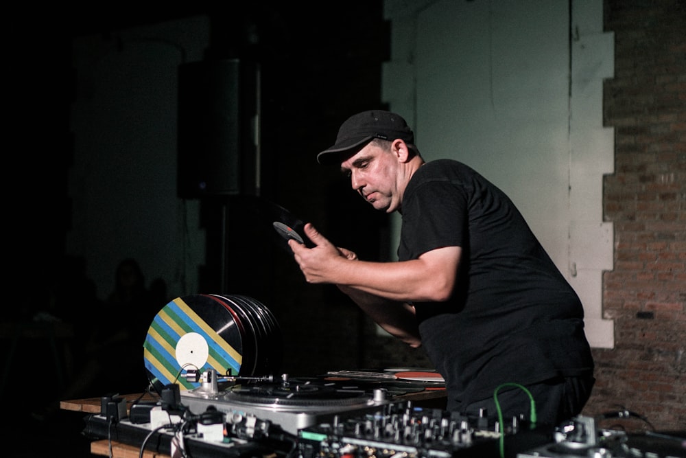 man in black crew neck t-shirt and black cap playing dj mixer