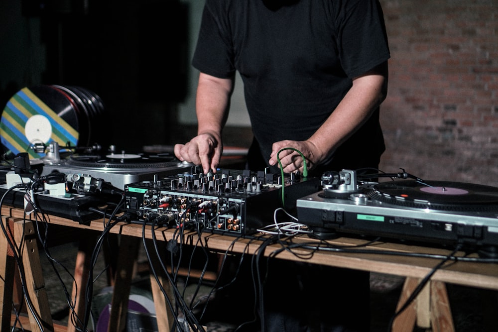 man in black crew neck t-shirt standing in front of dj mixer