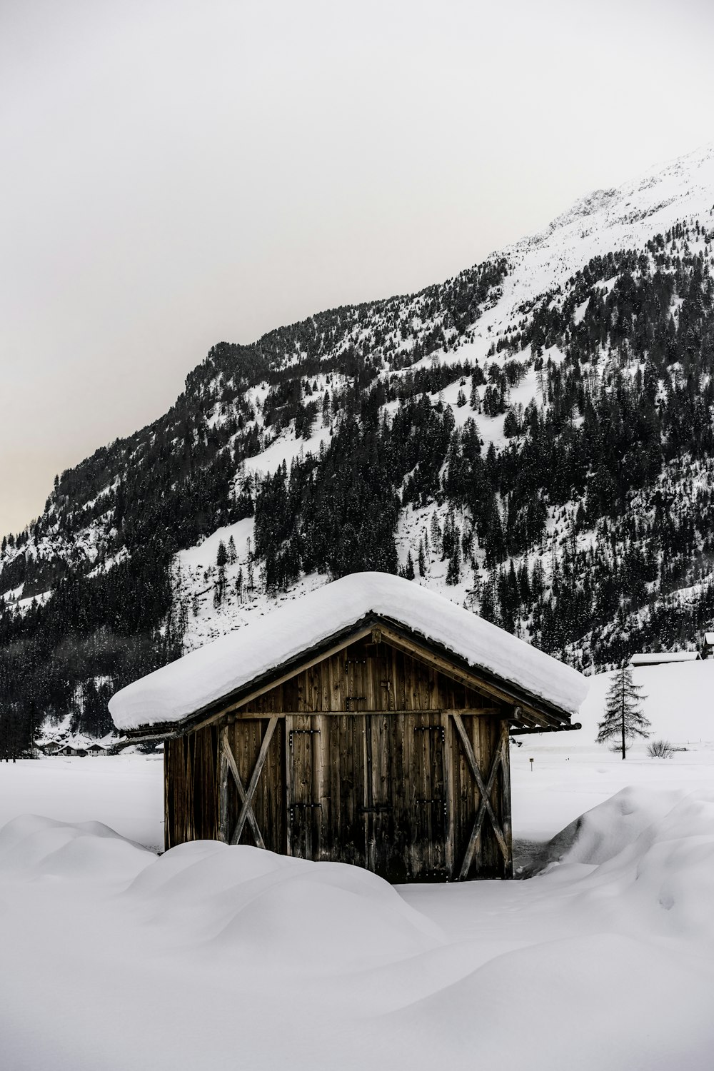 brown wooden house on snow covered ground near snow covered mountain during daytime