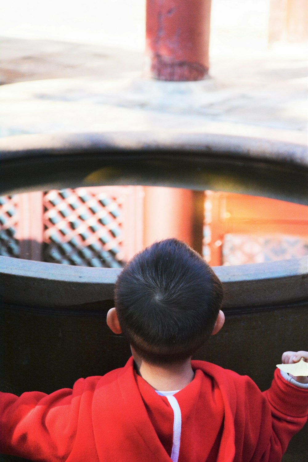 a young boy in a red jacket holding a white frisbee