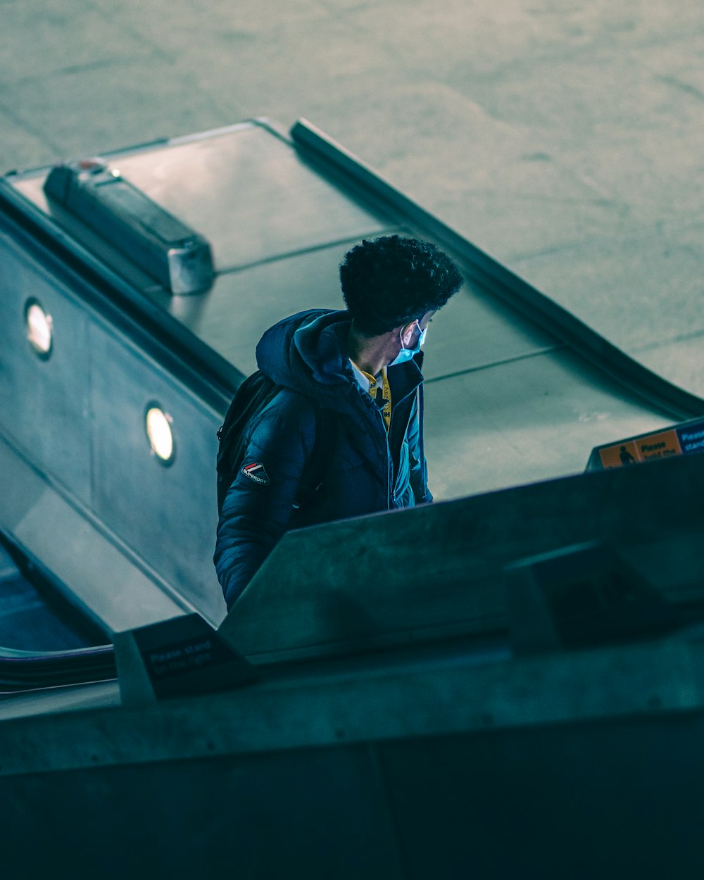 man in blue and red jacket standing beside black wooden table