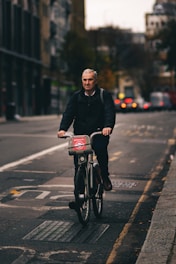 man in black jacket riding bicycle on road during daytime