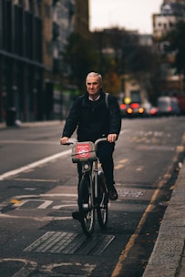 man in black jacket riding bicycle on road during daytime