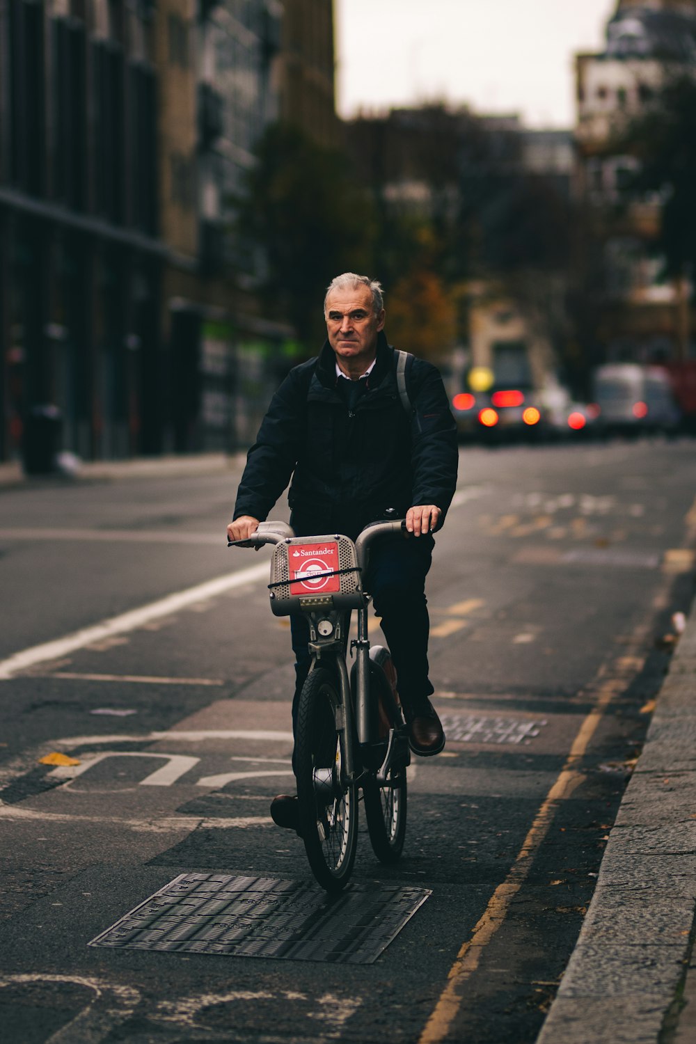 man in black jacket riding bicycle on road during daytime