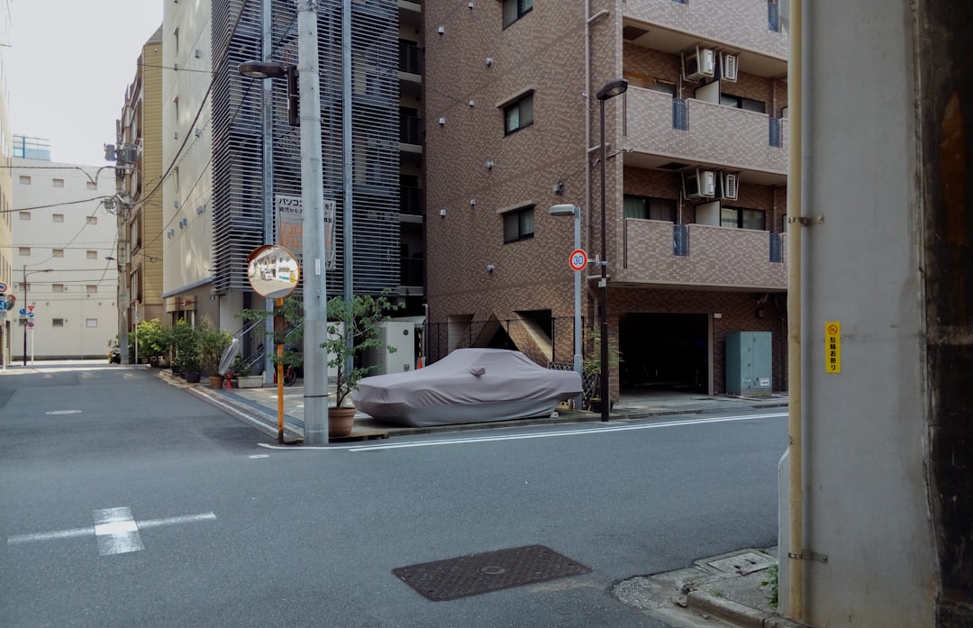 white car on road near brown building during daytime