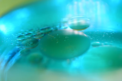 Close-up of a translucent membrane filter with abstract pore structures glowing softly in deep teal and cyan hues.