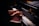 Hands playing on a grand piano with visible brand markings, with sheet music placed above the keys. The lighting is soft, highlighting the player's hands and the piano keys.