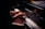 Hands playing on a grand piano with visible brand markings, with sheet music placed above the keys. The lighting is soft, highlighting the player's hands and the piano keys.