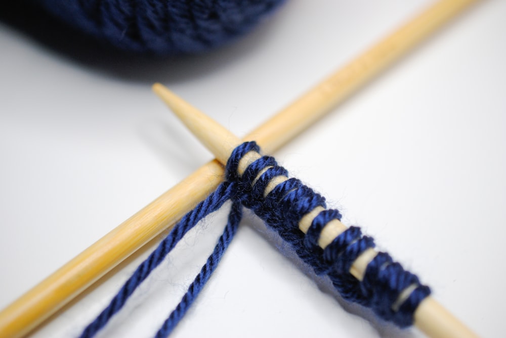 black yarn beside brown wooden stick