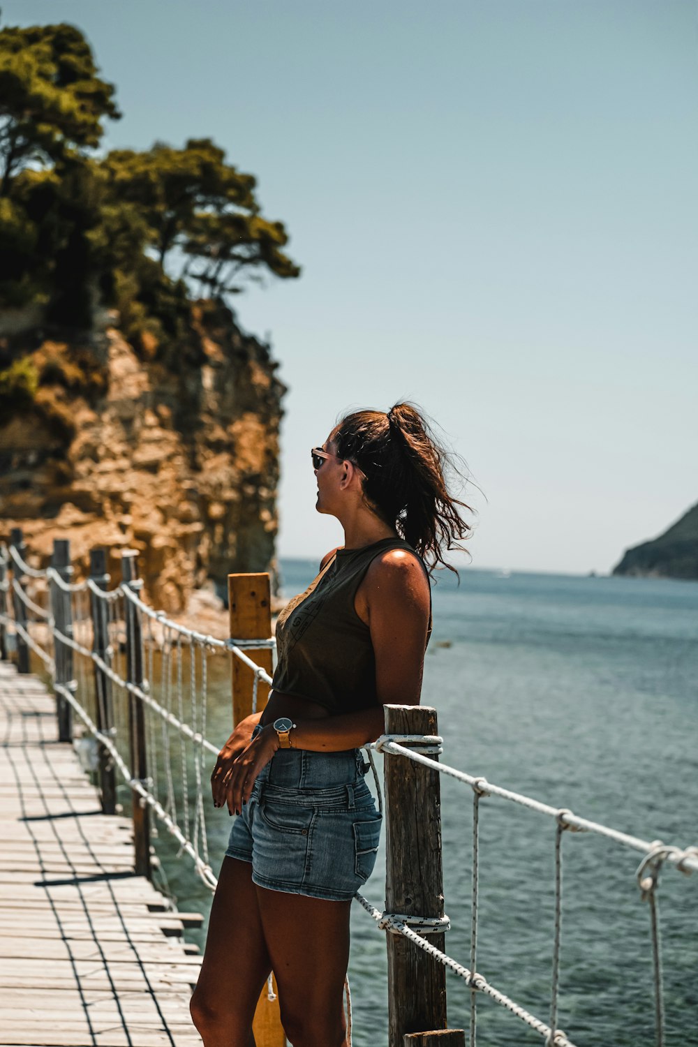 woman in blue denim shorts standing on bridge during daytime