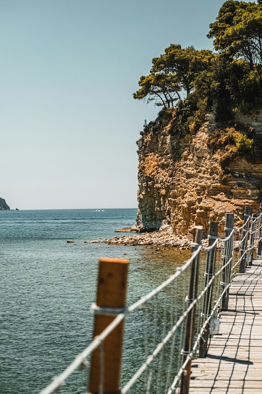 brown wooden fence on brown rock formation near body of water during daytime