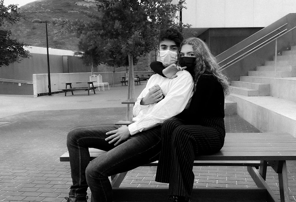 grayscale photo of couple sitting on bench