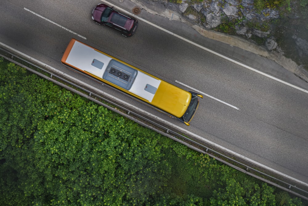 an aerial view of a yellow and white bus on a road