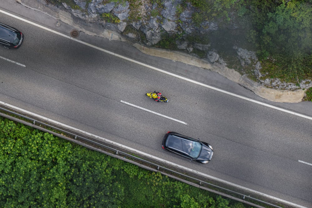 a car driving down a road next to a lush green hillside