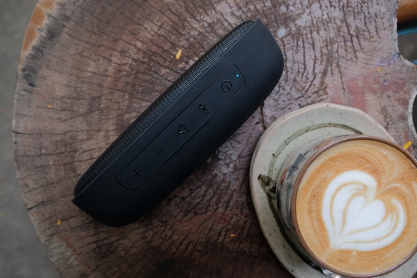 A sleek wireless speaker resting on a wooden table, surrounded by coffee cups.