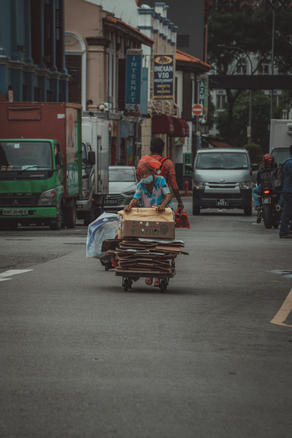 woman in red and white dress sitting on brown wooden cart on street during daytime