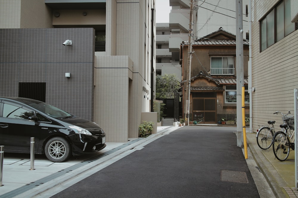 black car parked beside white building during daytime