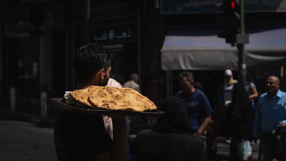 man in black shirt sitting in front of pizza