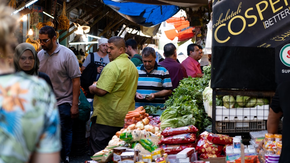 man in green polo shirt standing in front of vegetable stand