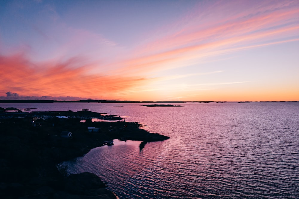 silhouette of houses near sea during sunset