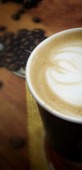 Close up of a steaming cup of coffee with latte art on a dark wooden table