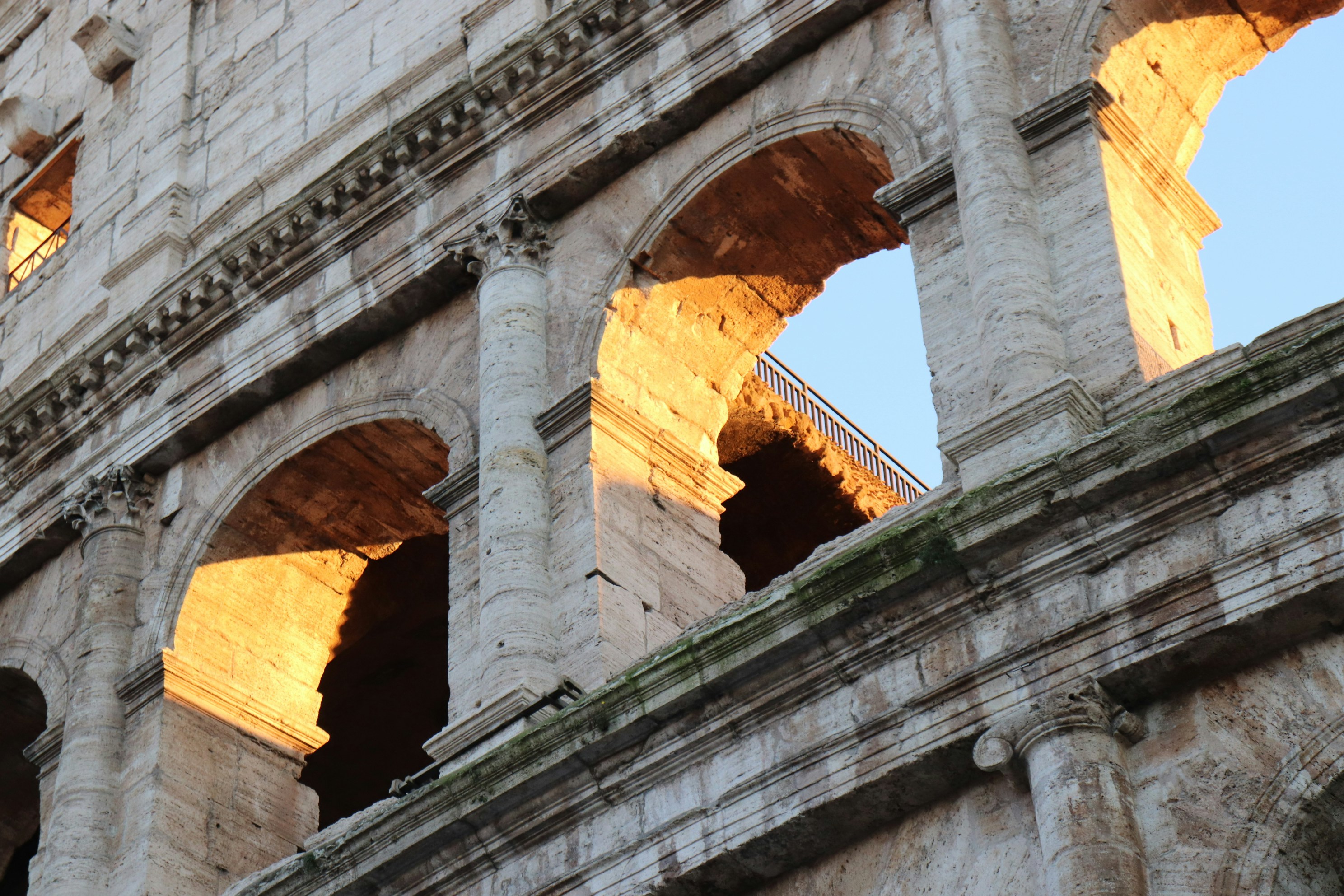 Golden rays of sunlight emerging through the arches of the impressive colosseum in the heart of Rome, Italy.