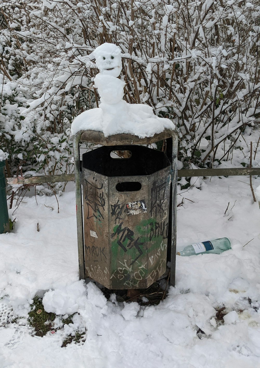 green and brown trash bin on snow covered ground