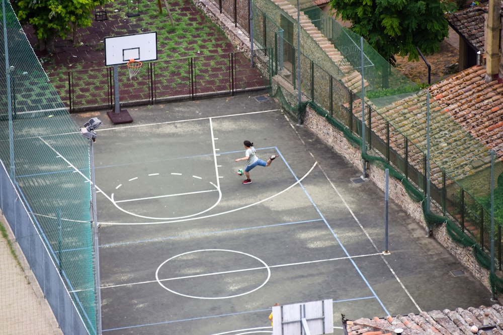 Mujer con camisa blanca sentada en la cancha de baloncesto durante el día
