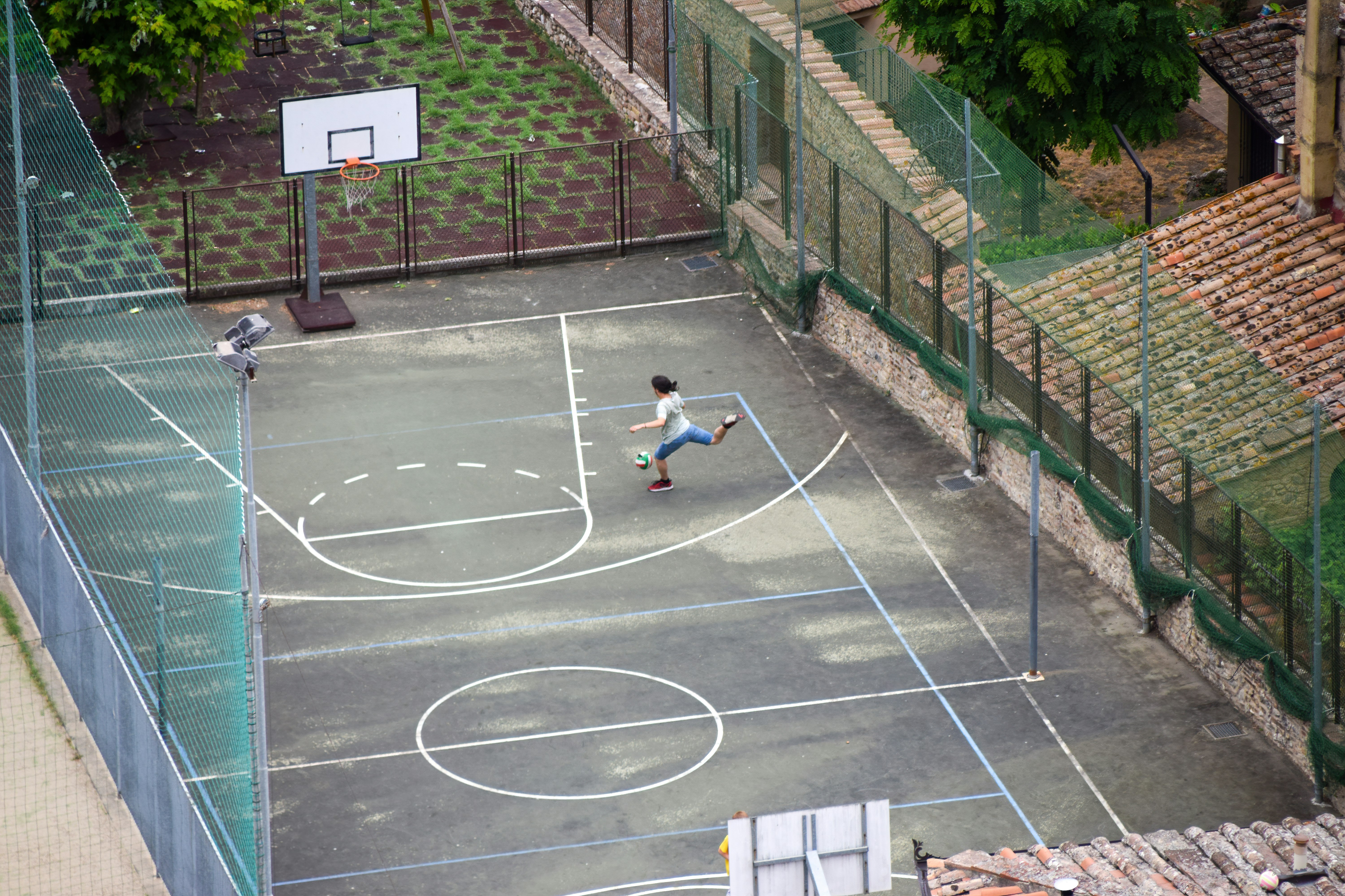 woman in white shirt sitting on basketball court during daytime