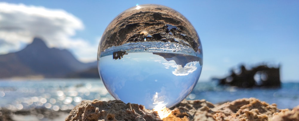 bola de vidro transparente na areia marrom durante o dia
