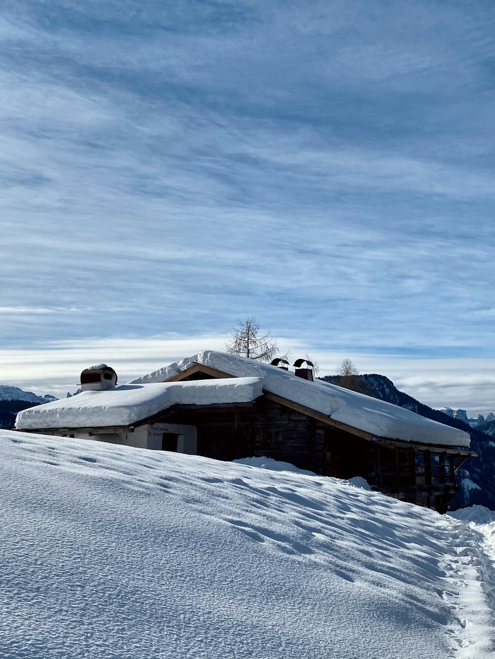casa de madeira marrom no chão coberto de neve sob o céu azul durante o dia