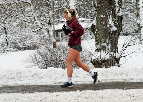 Person jogging outdoors wearing sleek Osseo Wave headphones, sunlight filtering through trees.