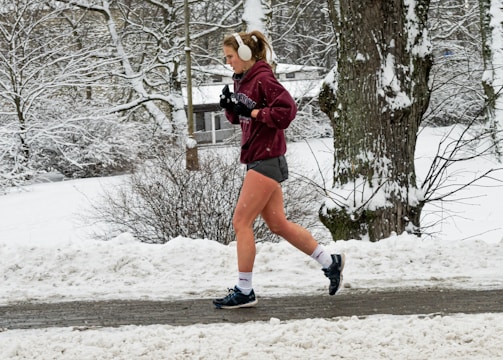 A person wearing wireless earbuds while jogging outdoors.
