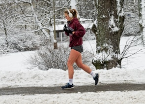 Person jogging outdoors wearing waterproof Bluetooth earphones.