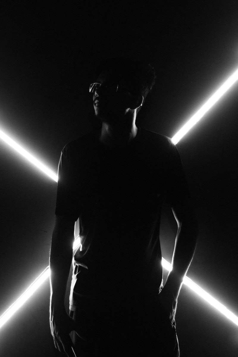 Black and white photo of a man standing in front of neon lights