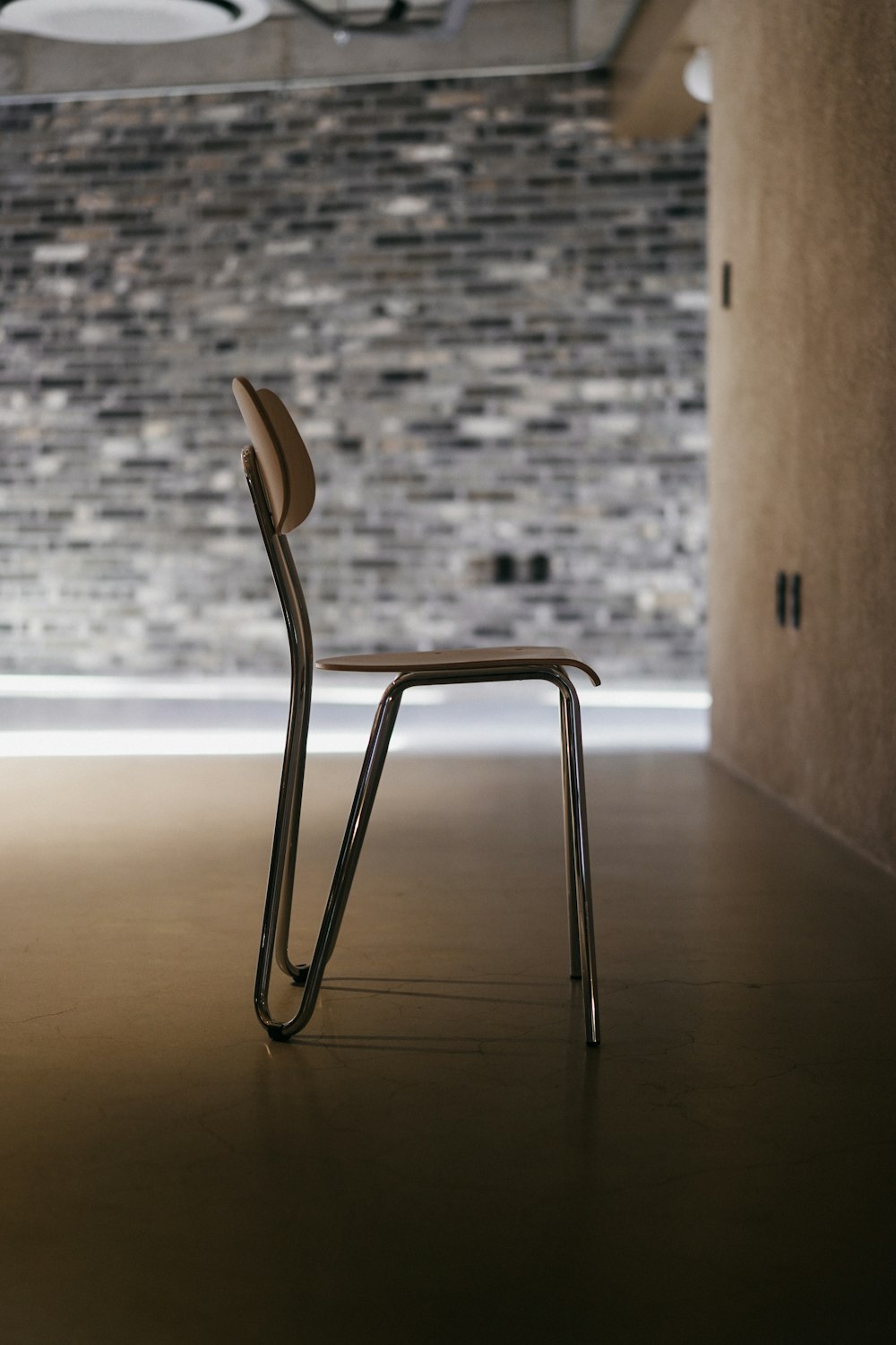 茶色の木製の壁の横にあるステンレス製の椅子