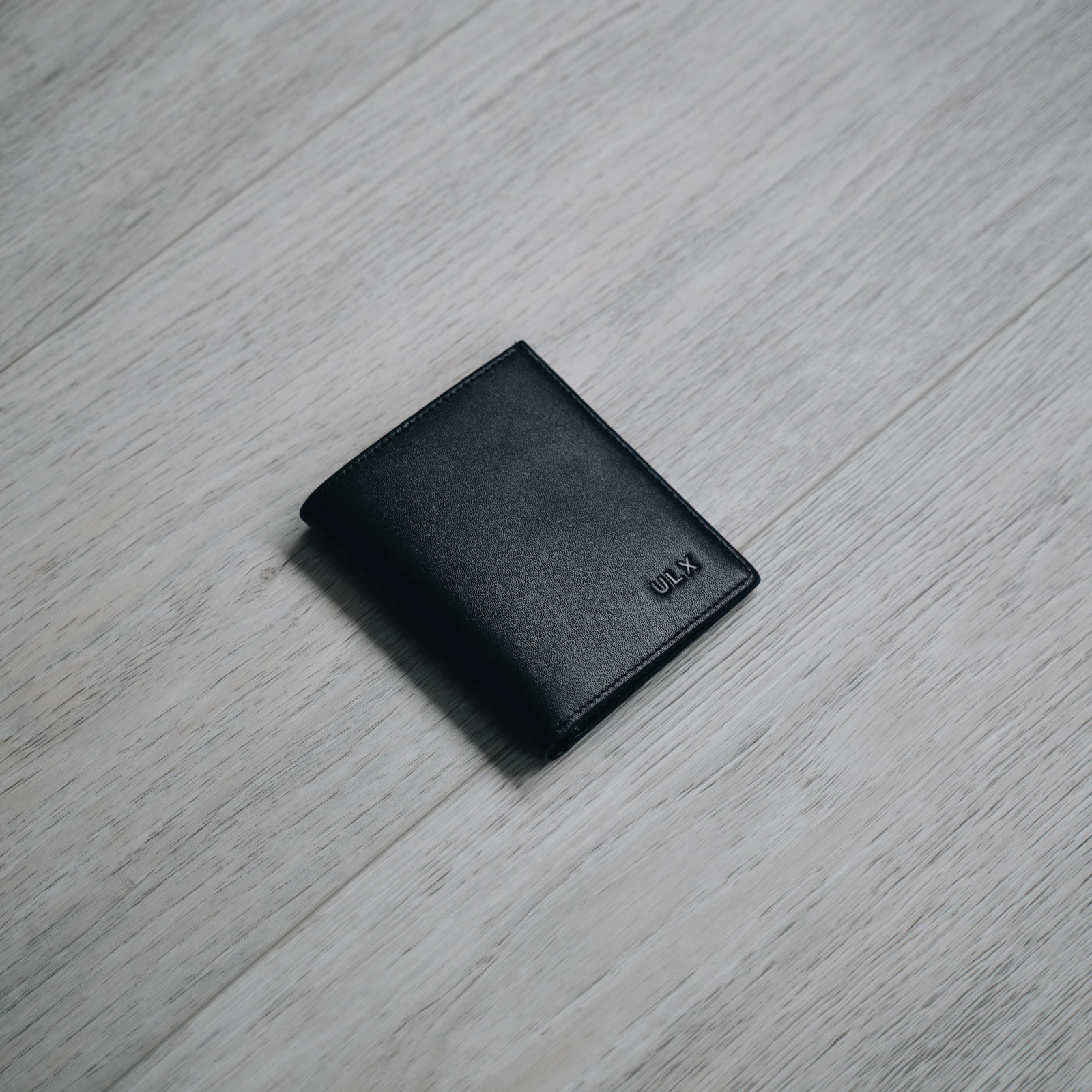 Black leather bifold wallet on wood